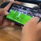 Seorang pemain memainkan game FC Mobile EA Sports melalui ponsel saat pertandingan virtual berlangsung.