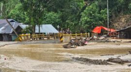 Luapan Sungai Batang di Palembayan, Agam, menutup akses jalan setelah hujan deras. Kayu gelondongan tampak tersangkut di jembatan, membuat arus semakin deras.
