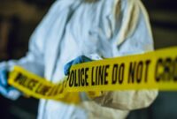 Petugas forensik memasang garis polisi di lokasi kejadian perkara untuk mengamankan area penyelidikan.