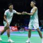 Dua pebulu tangkis ganda putra Indonesia saling berjabat tangan di tengah pertandingan pada turnamen internasional.