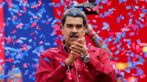 Presiden Venezuela tampil di hadapan pendukungnya saat sebuah acara politik, dengan konfeti berhamburan di latar belakang.
