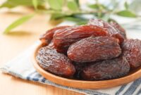 Kurma medjool segar dengan tekstur lembut dan warna cokelat pekat tersaji dalam mangkuk kayu.