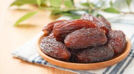 Kurma medjool segar dengan tekstur lembut dan warna cokelat pekat tersaji dalam mangkuk kayu.