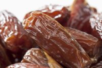 Tampilan kurma Tunisia jenis deglet nour yang memiliki warna cokelat keemasan, permukaan halus, dan daging buah semi-transparan.