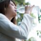 Seorang perempuan meminum air putih dari botol sebagai upaya memenuhi kebutuhan cairan tubuh.