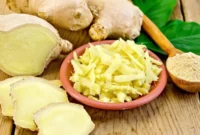 Jahe segar dalam bentuk irisan dan parutan yang disajikan bersama bahan alami lainnya di atas permukaan kayu.