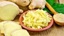 Jahe segar dalam bentuk irisan dan parutan yang disajikan bersama bahan alami lainnya di atas permukaan kayu.