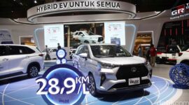 Pengunjung melihat Toyota Veloz Hybrid 2026 di showroom sambil membaca informasi harga dan estimasi pajak tahunan mobil hybrid tersebut.