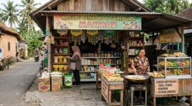 Seorang pedagang melayani pembeli di warung sembako sekaligus menjual gorengan di teras rumah