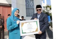 Wali Kota Sungai Penuh, Alfin, menyerahkan penghargaan kepada Ketua TP PKK Sri Kartini Alfin sebagai penggagas Gerakan 3S dalam apel Hari Kebangkitan Nasional 2026.