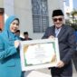 Wali Kota Sungai Penuh, Alfin, menyerahkan penghargaan kepada Ketua TP PKK Sri Kartini Alfin sebagai penggagas Gerakan 3S dalam apel Hari Kebangkitan Nasional 2026.