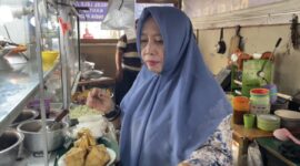 Bude Puji melayani pembeli sekaligus membagikan nasi gratis kepada penumpang dan pedagang di Pelabuhan Bakauheni.