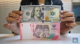 Petugas menghitung uang rupiah dan dolar AS, mencerminkan pelemahan nilai tukar rupiah terhadap dolar AS.(Fhoto CNBC Indonesia/Faisal Rahman)
