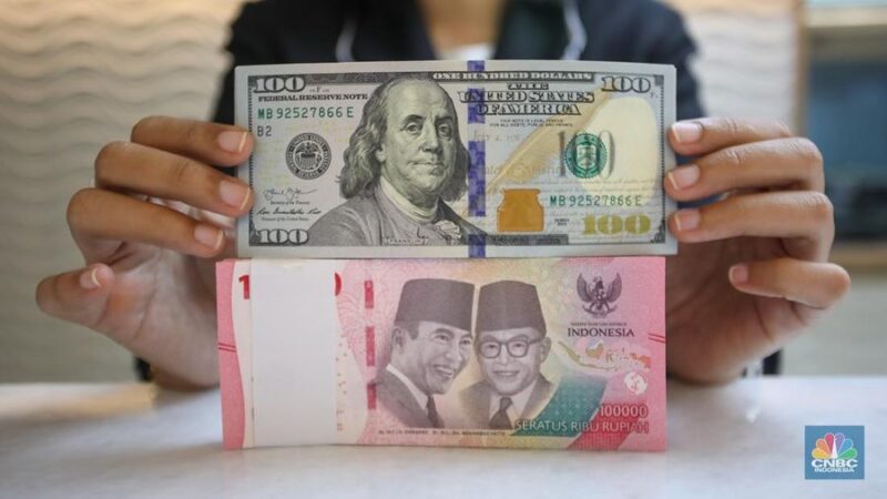 Petugas menghitung uang rupiah dan dolar AS, mencerminkan pelemahan nilai tukar rupiah terhadap dolar AS.(Fhoto CNBC Indonesia/Faisal Rahman)

