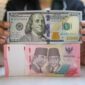 Petugas menghitung uang rupiah dan dolar AS, mencerminkan pelemahan nilai tukar rupiah terhadap dolar AS.(Fhoto CNBC Indonesia/Faisal Rahman)
