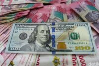 Lembaran uang dolar Amerika Serikat pecahan 100 dolar berada di atas tumpukan uang rupiah, menggambarkan penguatan dolar AS terhadap rupiah di pasar keuangan.(Ilustrasi/Foto: Gilang Faturahman/detikFoto)