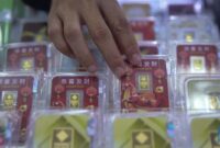 Petugas melayani pembeli dalam transaksi jual beli emas Antam di butik logam mulia.