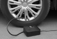 Pompa angin elektrik portable mengisi ban mobil di jalan(NewAfrica/Depositphotos)