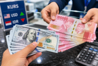Ilustrasi Petugas menunjukkan uang rupiah saat transaksi penukaran dengan dolar AS di counter bank.