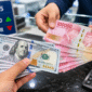 Ilustrasi Petugas menunjukkan uang rupiah saat transaksi penukaran dengan dolar AS di counter bank.
